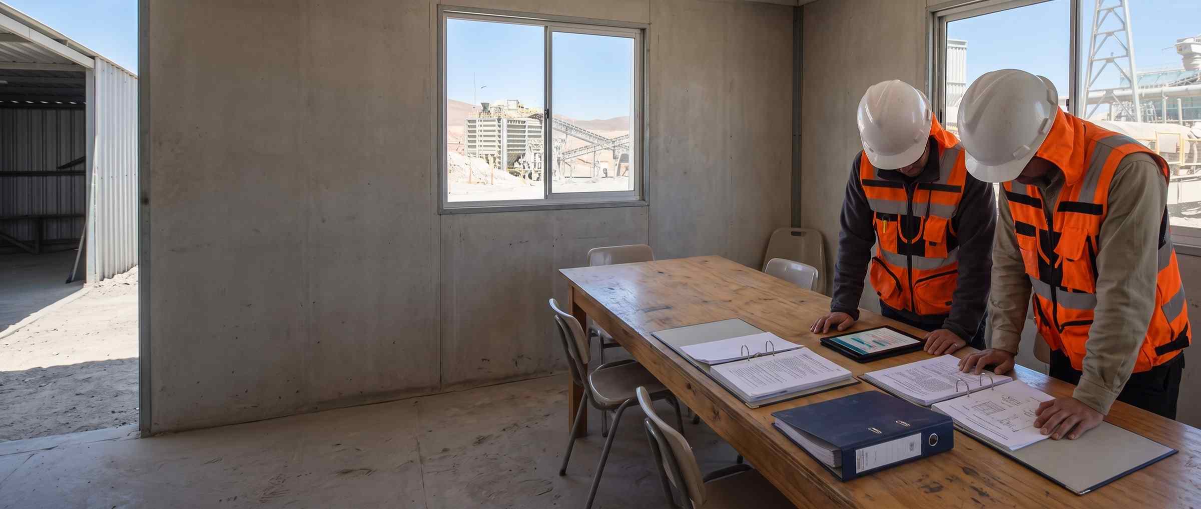Tres archivadores de palanca abiertos sobre la mesa de una sala de faena, junto al procedimiento impreso y una tablet.