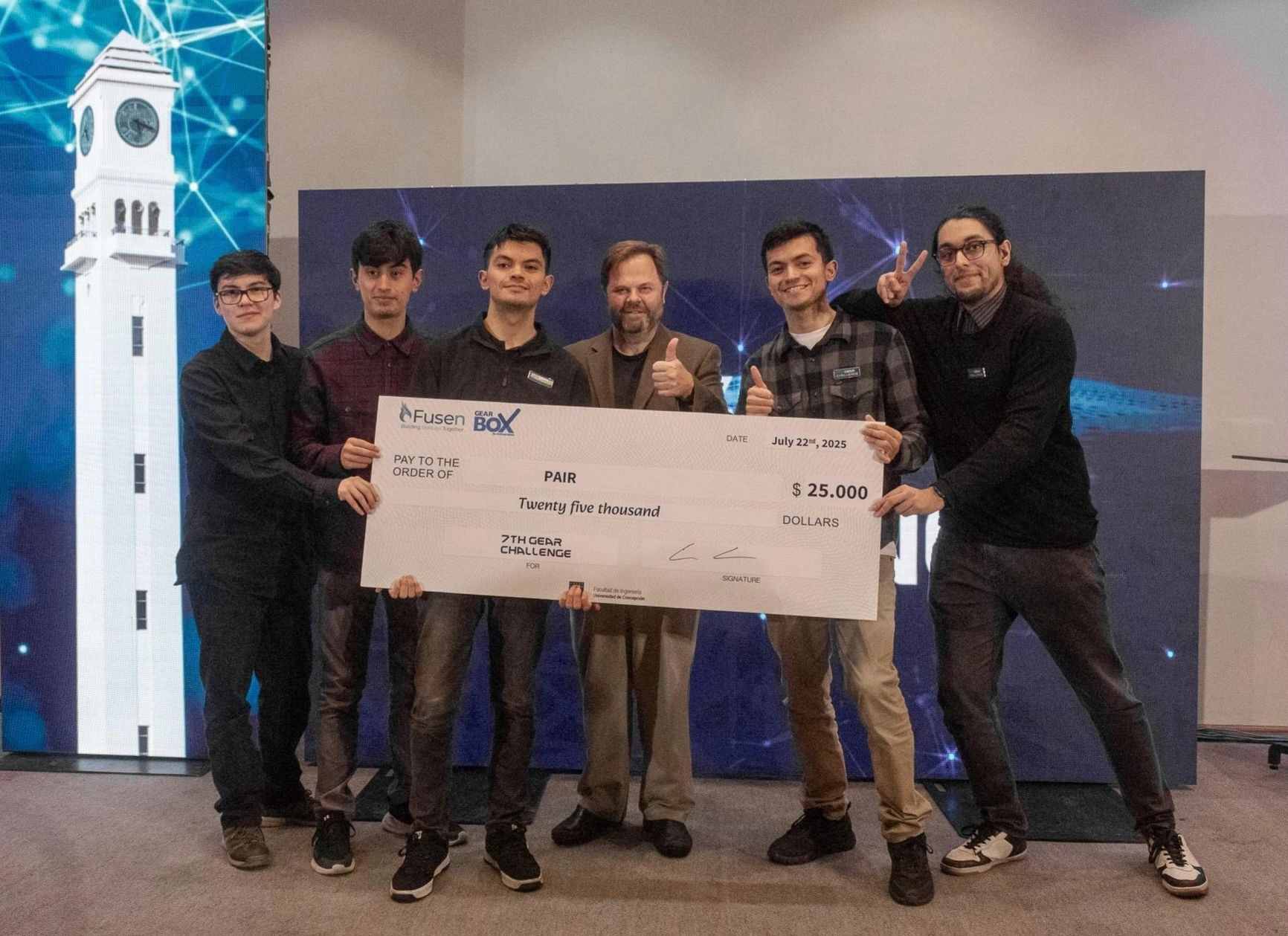 El equipo de PAIR sobre el escenario sosteniendo el cheque simbólico de veinticinco mil dólares del 7th Gear Challenge, con la marca de Fusen y de Gearbox.